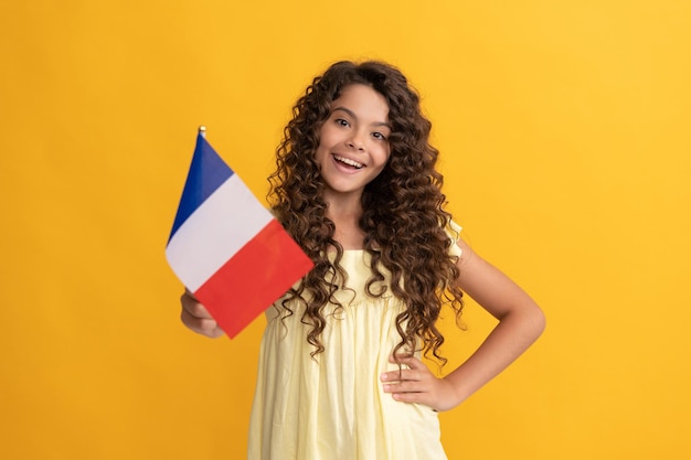 Cabelo longo cacheado de criança feliz segura a bandeira francesa, frança.