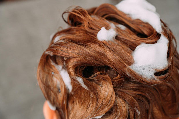 Cabelo ruivo com espuma de xampu fecha foco seletivo