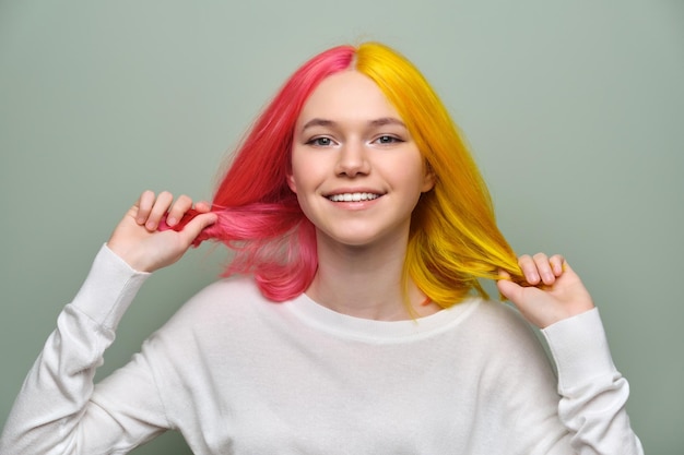 Cabelos longos tingidos closeup menina moda modelo de beleza mostrando coloração em seu cabelo fundo verde estúdio coloração profissional tendências da moda beleza