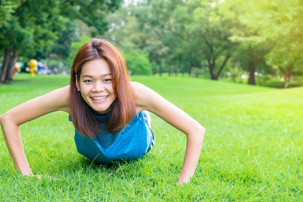 Caber mulher asiática sorrir e fazer flexões no parque