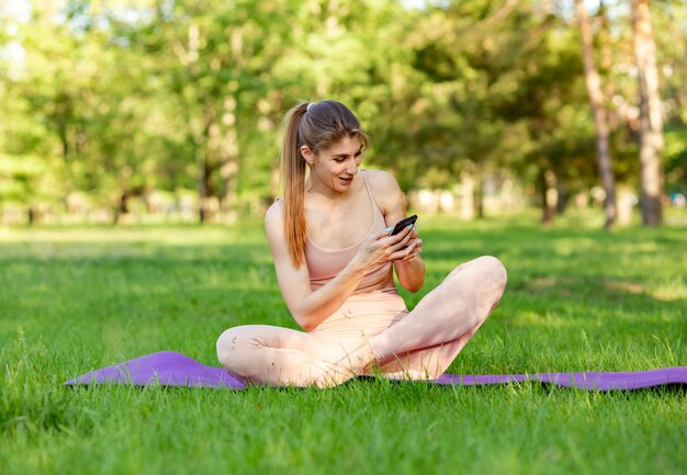 Caber mulher fazendo yoga e assistindo tutoriais on-line no telefone inteligente