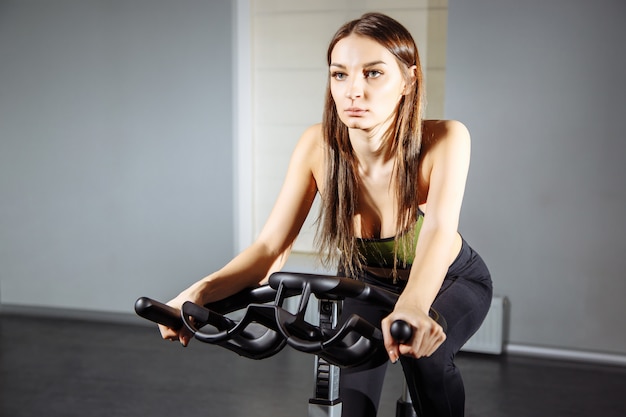 Foto caber mulher malhando na bicicleta ergométrica no ginásio