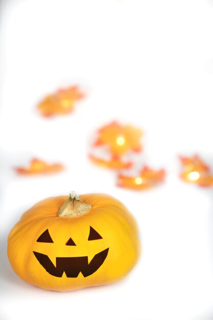 Cabeza de calabaza naranja para halloween en la mano scary head jack o lantern con hojas de otoño cayendo