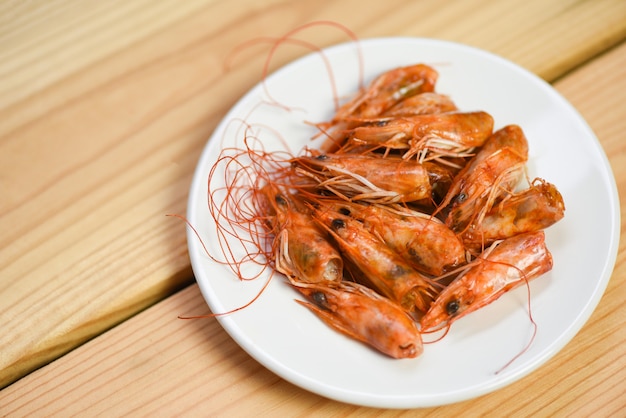 Cabeza de camarón crujiente frita deliciosas especias condimento en placa y fondo de mesa de madera. gambas o langostinos cocidos Mariscos egoístas