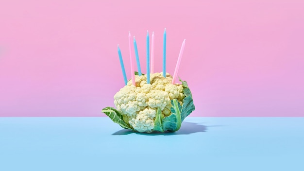 Foto cabeza de coliflor de coliflor sobre un fondo de colores brillantes con velas navideñas pastel de cumpleaños