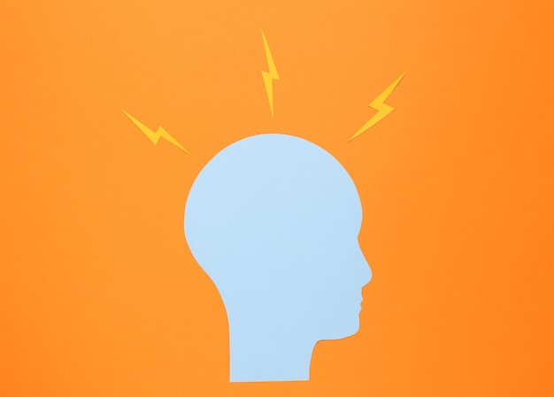 Cabeza humana cortada en papel con flechas en fondo naranja dolor de cabeza tormenta de ideas o flujo de ideas concepto
