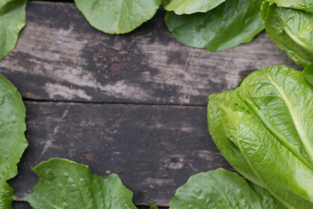 Foto cabeza de lechuga de mantequilla sobre fondo de madera rústica.