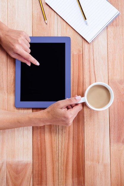 Cabeza de manos femeninas usando tableta y sosteniendo café