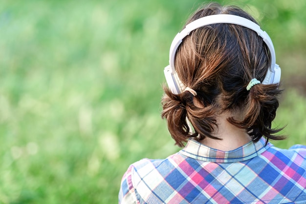 Cabeza de una niña con auriculares primer plano en la naturaleza soleada