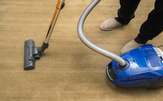 Foto cabeza oscura de una aspiradora moderna que se utiliza al aspirar una alfombra. concepto de servicio de limpieza. proceso de aspiración de alfombras con aspiradora