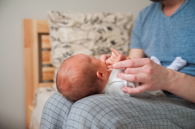 Cabeza de un recién nacido de cerca. El padre tiene en las manos del niño y copia el espacio. Concepto de cuidado del bebé.