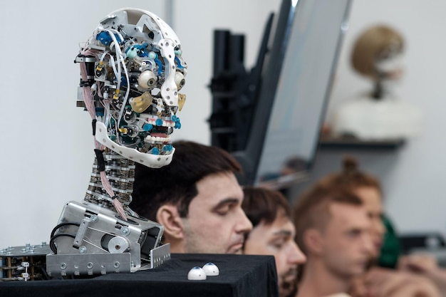 cabeza de robot antropomórfico capaz de imitar emociones sin una piel de cáscara exterior contra el fondo de varias pieles faciales intercambiables