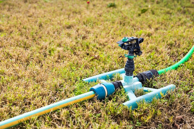 Cabezal de aspersor para rociar agua sobre la hierba verde.