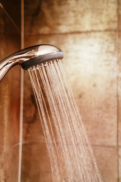 Foto cabezal de ducha y agua corriente en un baño.