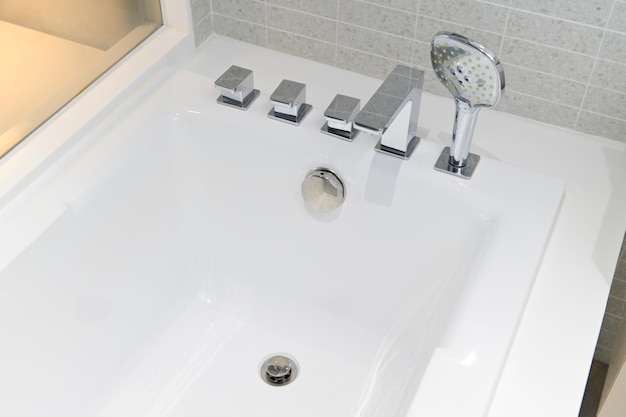 Cabezal de ducha y bañera de grifo en baño blanco
