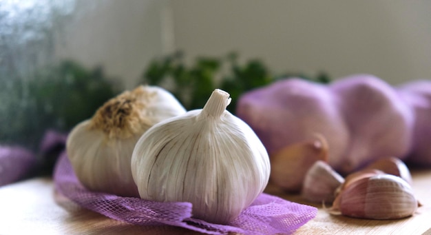 Cabezas de ajo sobre tela morada y dientes de ajo sobre una tabla de madera