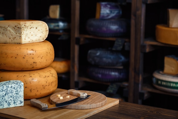 Cabezas de queso con rebanadas y cuchillos en una tabla de madera con un interior