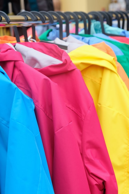 Foto cabide na loja com jaquetas de cores diferentes da moda à venda.