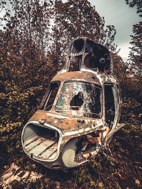 Cabina destruida abandonada del viejo helicóptero de la urss con vidrios rotos en el primer plano de la naturaleza salvaje