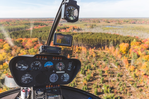 Cabina de helicóptero en vuelo sobre madera de otoño