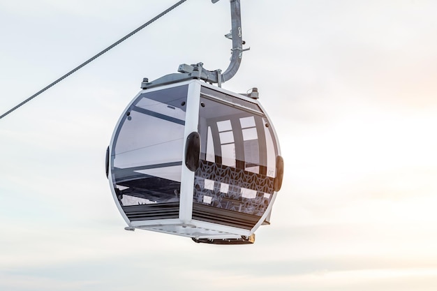 Foto cabina de un teleférico de góndola suspendida en una cuerda donde se sienta a la gente con esquís y tablas de snowboard en lo alto de las montañas de altai con nieve y cielo azul en la puesta de sol de invierno estaciones de esquí y snowboard