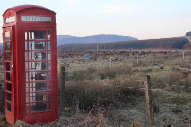 Cabina telefónica roja en el campo contra el cielo