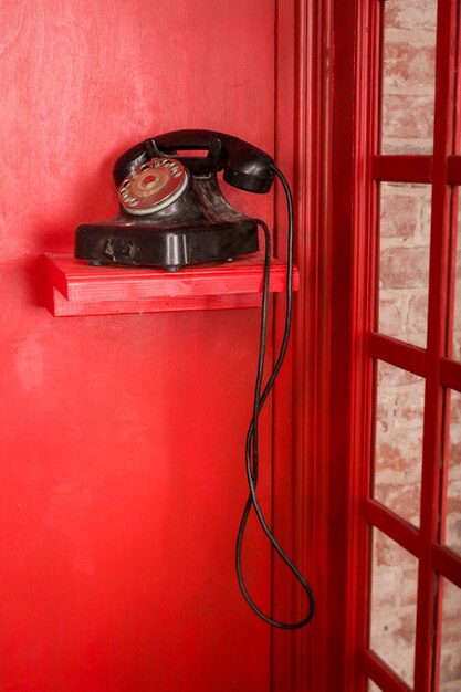 Foto cabina de teléfono roja en estilo británico con teléfono retro negro de pie en él