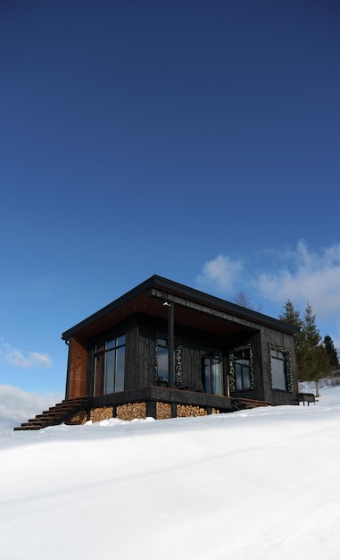 Cabine minúscula preta moderna em tempo nevado com céu azul claro