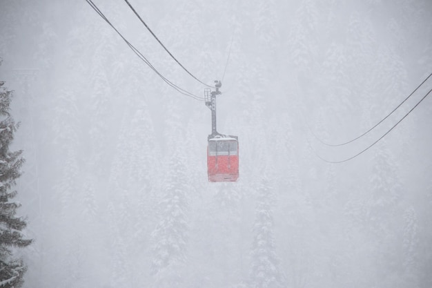 Cabine skilift vermelha na forte nevasca nas montanhas do Cáucaso