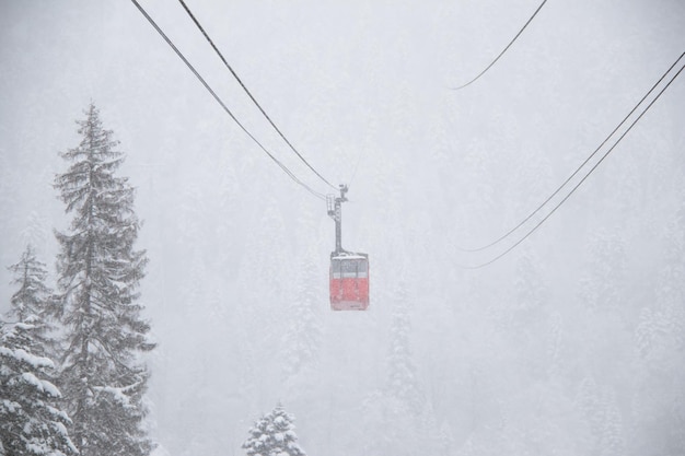 Cabine skilift vermelha na forte nevasca nas montanhas do Cáucaso