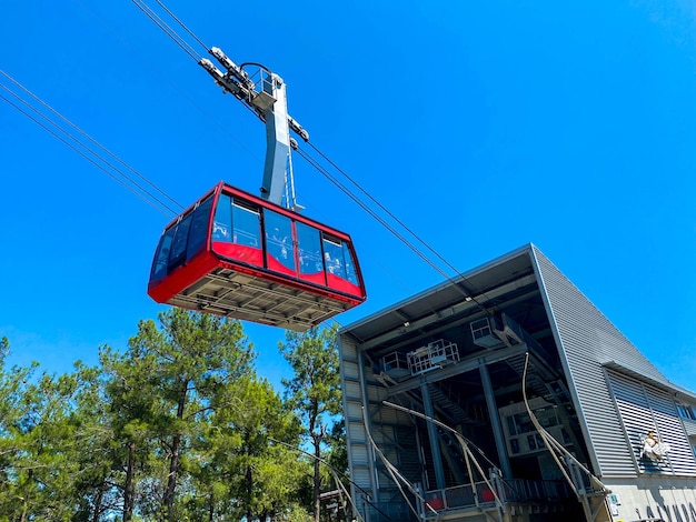 Cabine turística vermelha moderna do teleférico sobe as montanhas contra o céu azul