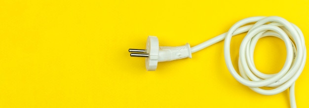 Cable de alimentación eléctrica blanco sobre fondo amarillo. Enchufe de la UE, tipo. Endecha plana, vista superior y foto de espacio de copia