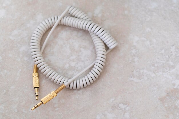 Cable de audio blanco con metal dorado sobre fondo de mármol