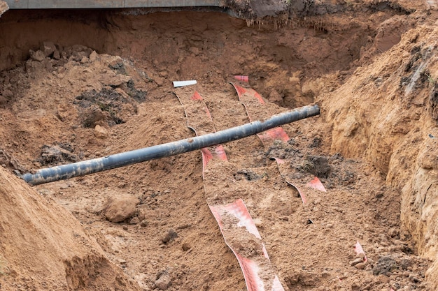 El cable eléctrico de alto voltaje se coloca en una zanja debajo de las redes de alcantarillado de ingeniería existentes Tendido de un cable de alto voltaje para suministrar electricidad a los edificios