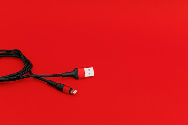 Cable usb negro sobre tecnología de tema de fondo rojo