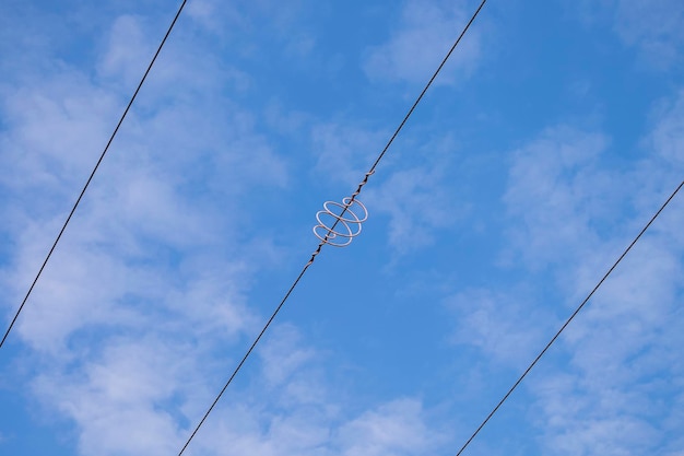 Foto cables de alta tensión con una bobina en espiral contra el cielo azul cable trenzado con servidumbre blanca industria electricidad