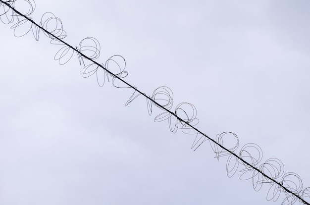 Foto cables de alta tensión con una bobina en espiral contra el cielo azul cable trenzado con servidumbre blanca industria electricidad