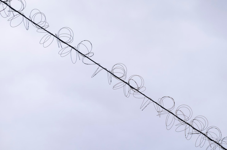 Foto cables de alta tensión con una bobina en espiral contra el cielo azul cable trenzado con servidumbre blanca industria electricidad