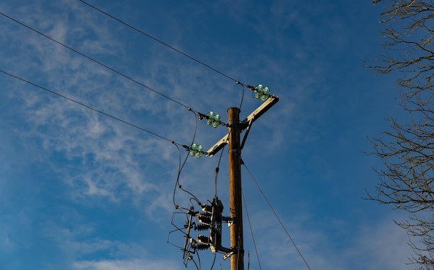 Cables eléctricos en un poste contra el cielo azul Suministro de electricidad