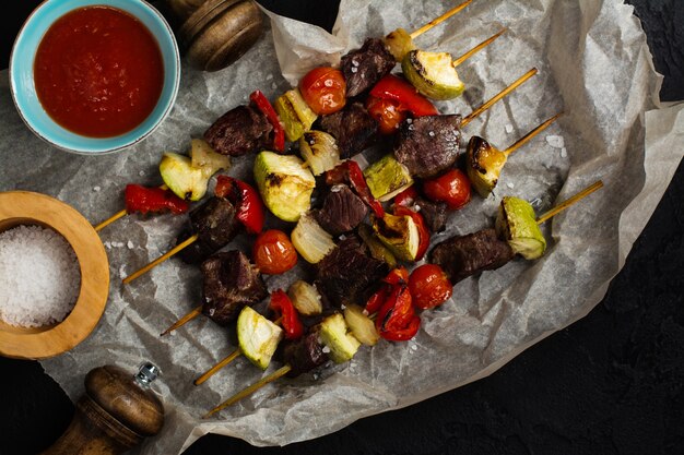 Cabos de carne y verduras a la parrilla sobre mesa de piedra negra