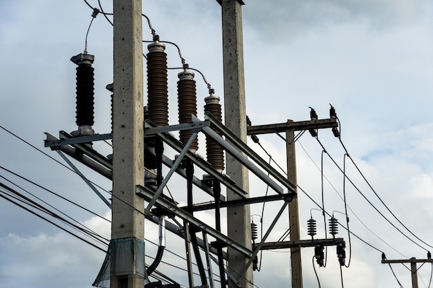 Cabos de alta tensão com isolador elétrico e equipamentos elétricos em subestação de energia.