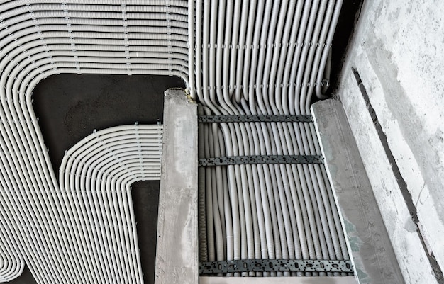 Cabos e tubulações elétricos na parede e no teto concretos da casa