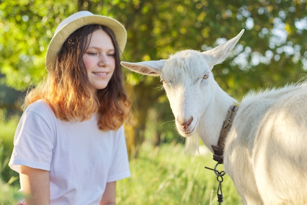 Cabra branca de fazenda doméstica no gramado com adolescente