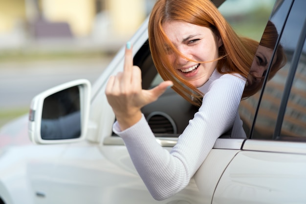 Foto cabreada, enojada, enojada, agresiva, conducía un automóvil gritándole a alguien con un gesto con el dedo medio.