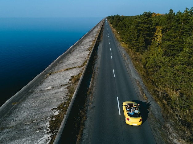 El cabriolet amarillo conduciendo por la carretera costera