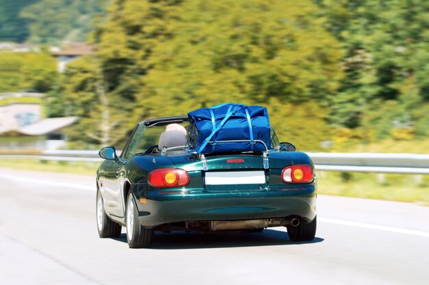 Cabriolet con bolsa de equipaje embalada en el asiento trasero en la carretera de Suiza.