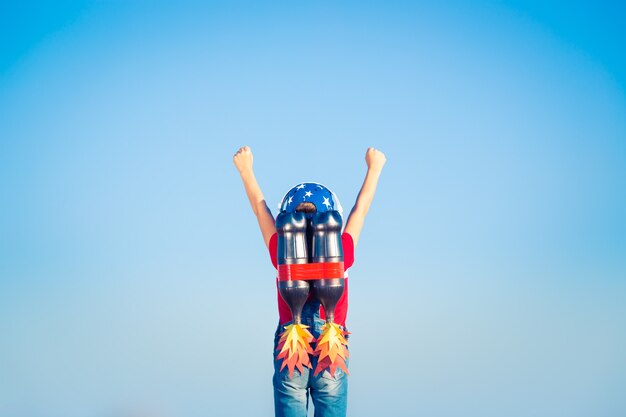 Cabrito con jet pack contra el cielo azul. Niño jugando al aire libre. Concepto de éxito, líder y ganador.