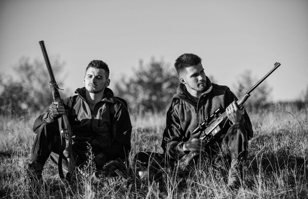 Caça com amigos passatempo lazer Descanso para homens de verdade conceito Caçadores guarda-caça relaxando Discutindo capturas Caçadores com rifles relaxando no ambiente natural Amigo caçador desfruta de lazer no campo