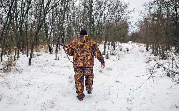 Caça de inverno. Hunter movendo-se com rifle e procurando por presas.