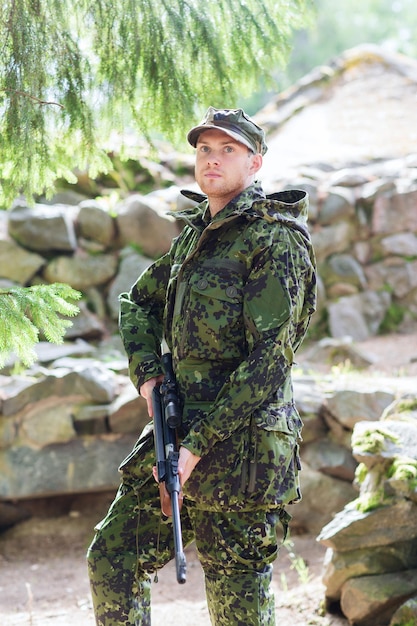 caça, guerra, exército e conceito de pessoas - jovem soldado, guarda florestal ou caçador com arma na floresta